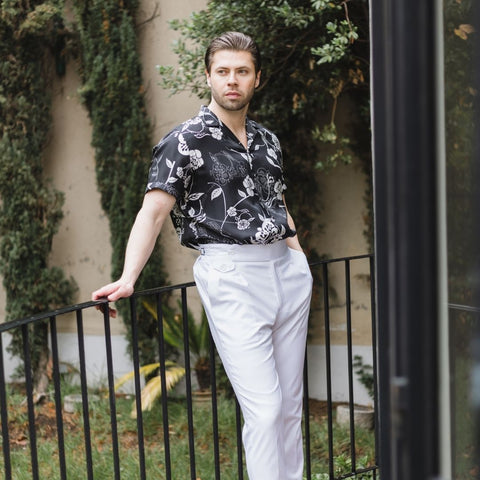 model standing on a balcony while wearing white pants and a short sleeve black gothic floral silk shirt from 1000 Kingdoms