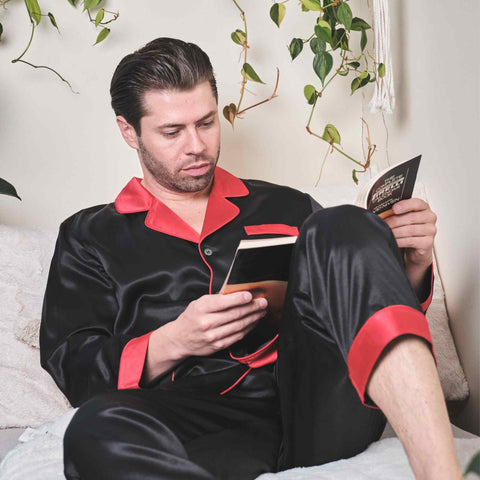 man sitting on a sofa reading a book wearing silky smooth 100% silk pajamas from 1000 Kingdoms